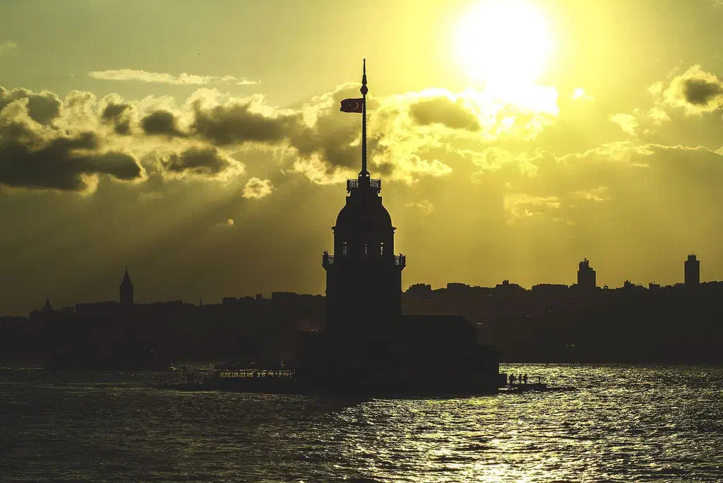 A private wooden yacht cruising the Bosphorus at golden hour with the strait glowing behind it