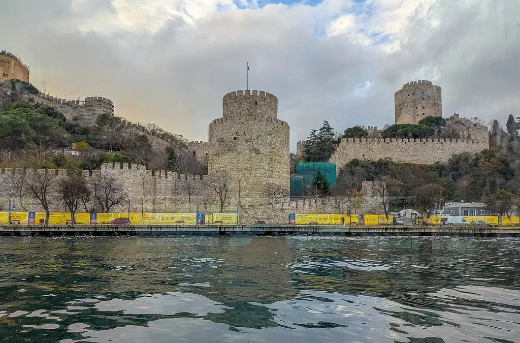 The ramparts of Rumeli Fortress on the European shore with the Bosphorus and a suspension bridge framed beyond the stone walls