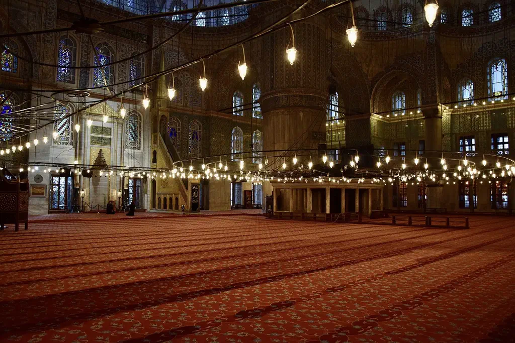 The interior of the Blue Mosque showing its blue İznik tiles and painted central dome